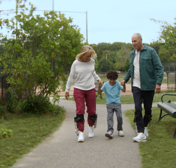 A family walking together on a park path wearing the Sidekick™
